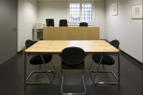 Gerichtssaal im Gefängnis Bässelergut mit Tisch und Stühlen darum.