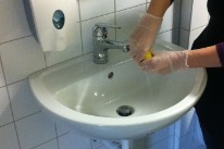Frau reinigt ein Waschbecken im Rahmen der gemeinnützigen Arbeit.